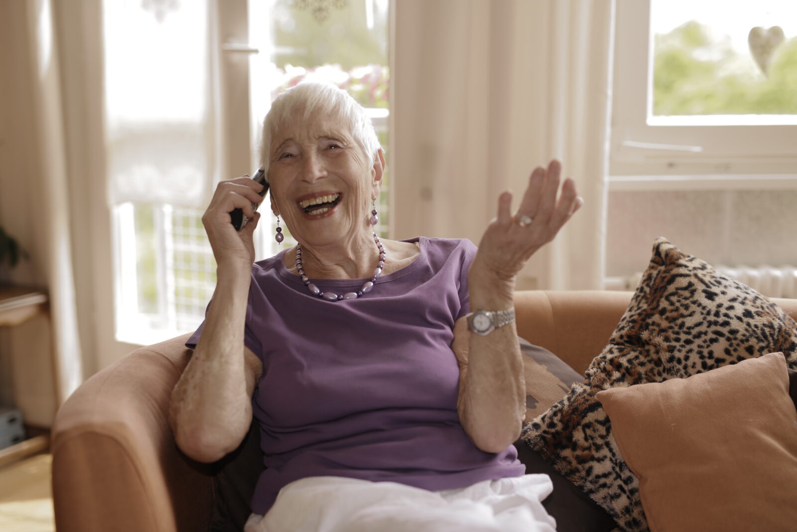 Ältere Person telefoniert und lacht herzlich