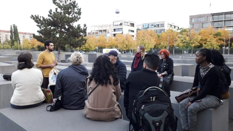 Eine Gruppe Menschen sitzt auf den Betonblöcken des Holocaustdenkmals