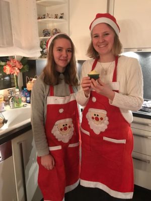Sofia und Josie tragen Weihnachtsschürzen und -mützen. Sie stehen in der Küche.
